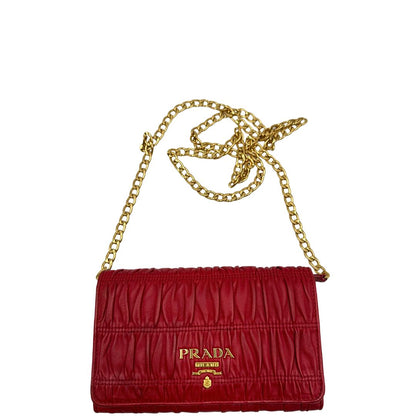 Front di un wallet Prada in pelle goffrata rossa, impreziosito da logo lettering sul front e specchietto interno; munito di una tracolla in catena amovibile e non regolabile. Completo di scatola.