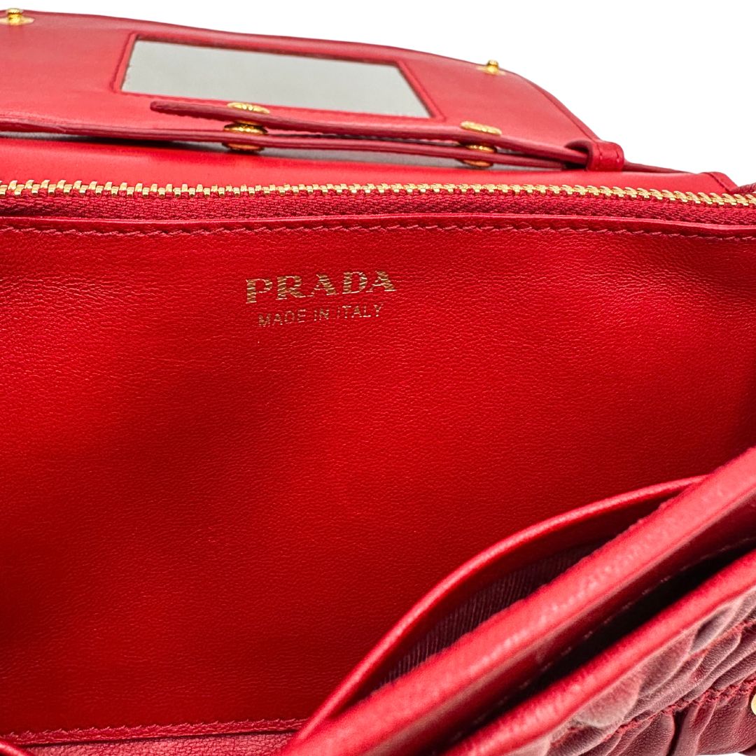 Interno di un wallet Prada in pelle goffrata rossa, impreziosito da logo lettering sul front e specchietto interno; munito di una tracolla in catena amovibile e non regolabile. Completo di scatola.