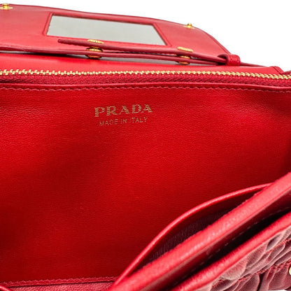Interno di un wallet Prada in pelle goffrata rossa, impreziosito da logo lettering sul front e specchietto interno; munito di una tracolla in catena amovibile e non regolabile. Completo di scatola.