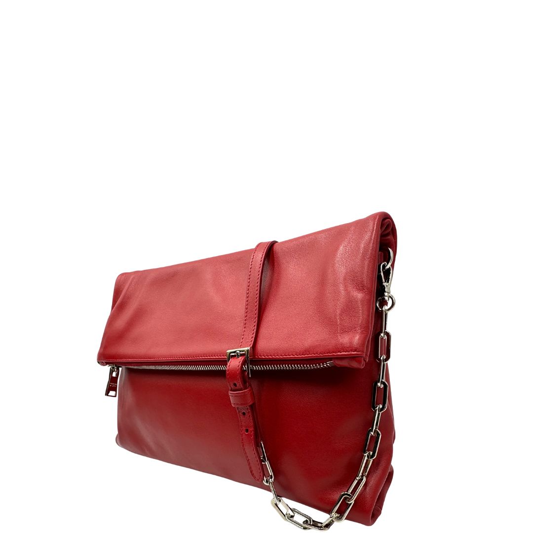 Laterale destro di una borsa a tracolla Prada in pelle rossa, munita di una tracolla in catena e pelle amovibile e regolabile. Completa di scatola.