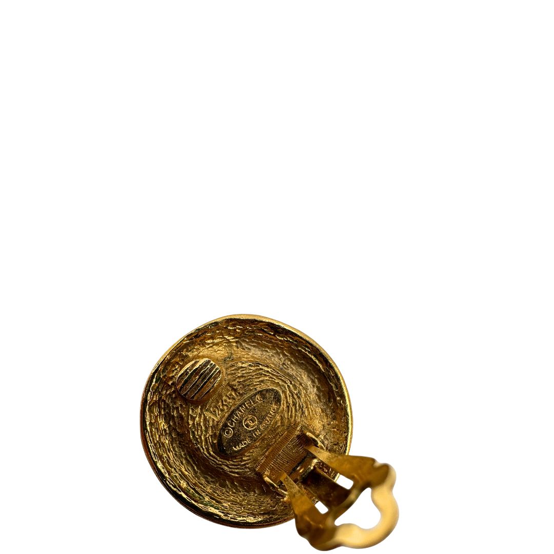 Orecchini Chanel vintage a clip, caratterizzati da una montatura in metallo dorato martellata che incornicia una grande perla artificiale centrale dal finish iridescente. Completi di scatola.