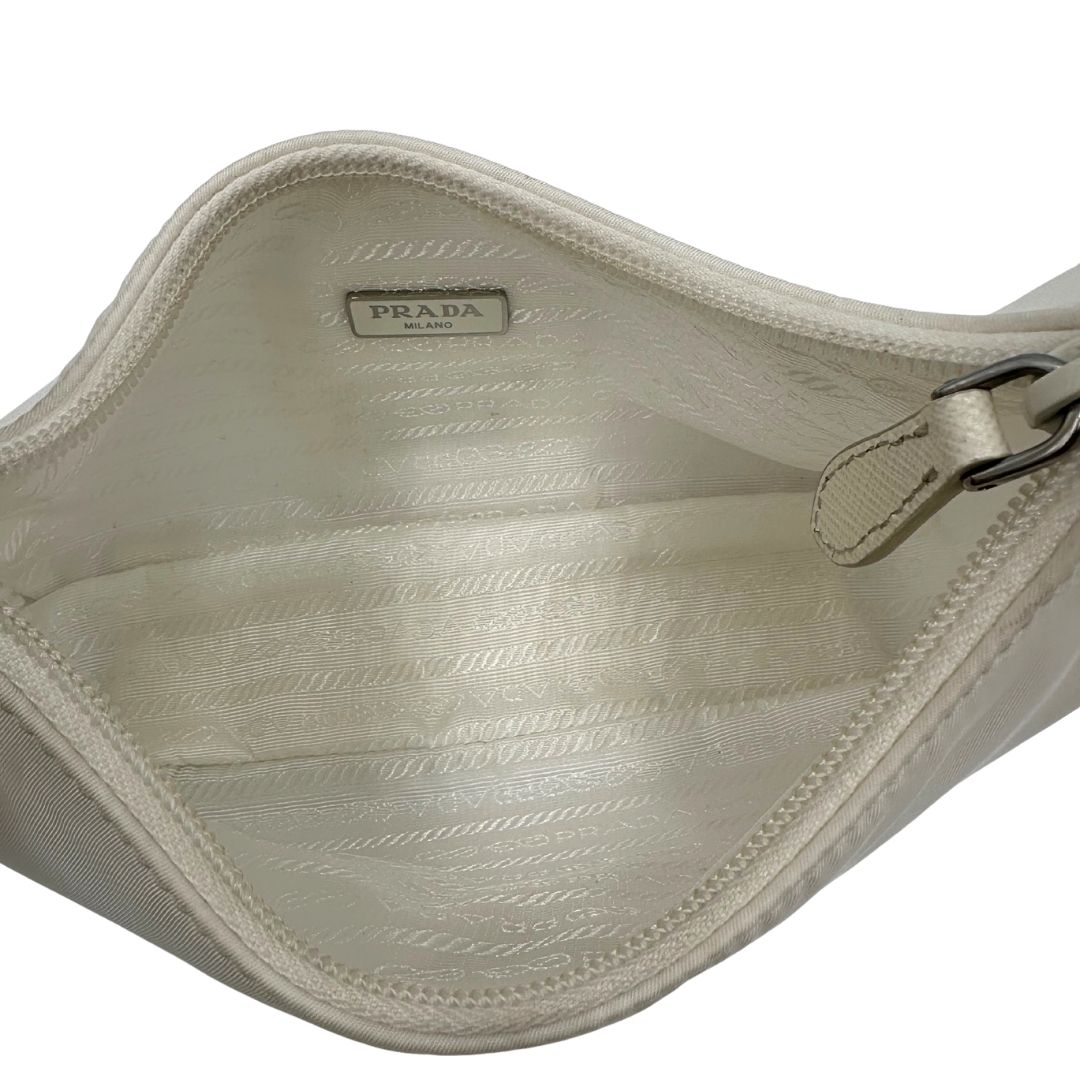 Interno di una borsa Prada Re-Edition 2000 in econylon color bianco gesso con dettagli in pelle Saffiano tono su tono e parti metalliche argentate. Completa di corredo.