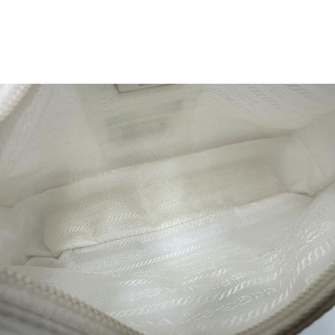 Interno di una borsa Prada Re-Edition 2000 in econylon color bianco gesso con dettagli in pelle Saffiano tono su tono e parti metalliche argentate. Completa di corredo.