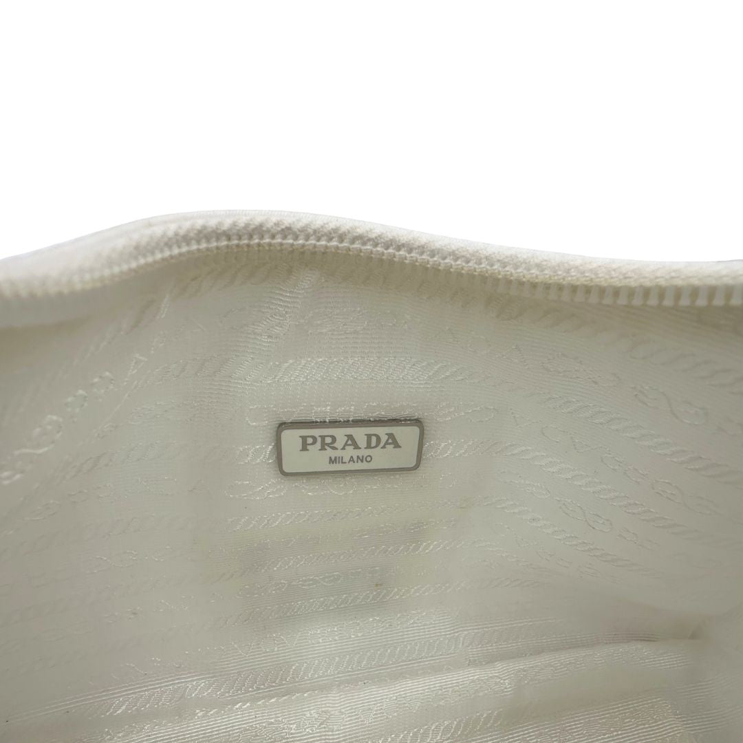 Interno di una borsa Prada Re-Edition 2000 in econylon color bianco gesso con dettagli in pelle Saffiano tono su tono e parti metalliche argentate. Completa di corredo.