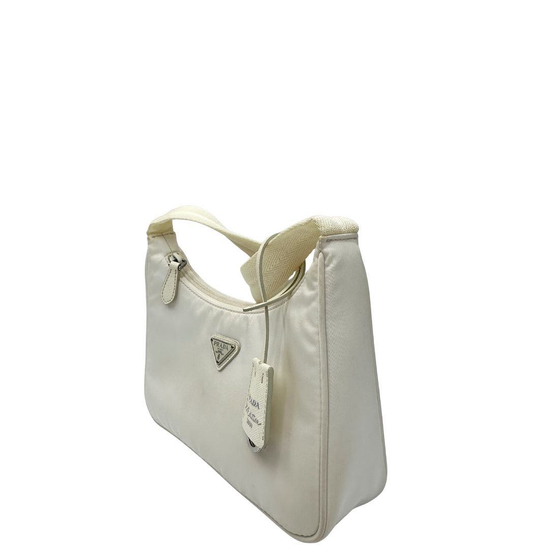Laterale destro di una borsa Prada Re-Edition 2000 in econylon color bianco gesso con dettagli in pelle Saffiano tono su tono e parti metalliche argentate. Completa di corredo.