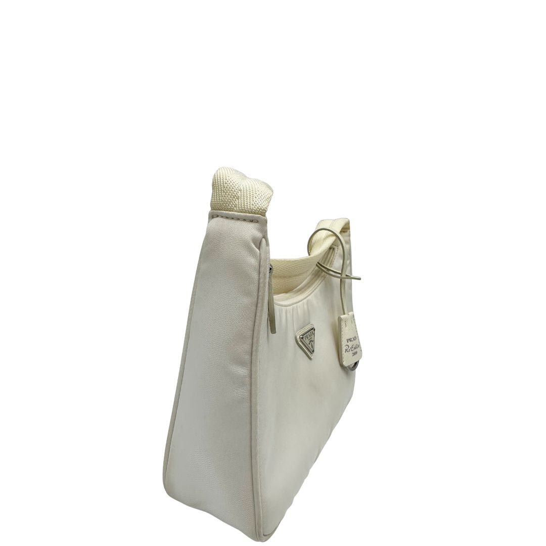 Laterale sinistro di una borsa Prada Re-Edition 2000 in econylon color bianco gesso con dettagli in pelle Saffiano tono su tono e parti metalliche argentate. Completa di corredo.