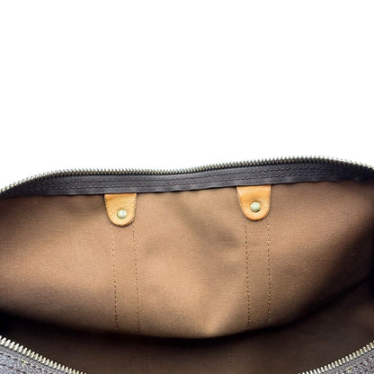 Interno di un Keepall Bandoulière in canvas monogram con finiture in vacchetta naturale e parti metalliche dorate; munito di doppi manici stondati e una tracolla amovibile e regolabile on spallaccio. Completo di lucchetto con chiave, tag porta address e ferma manici.