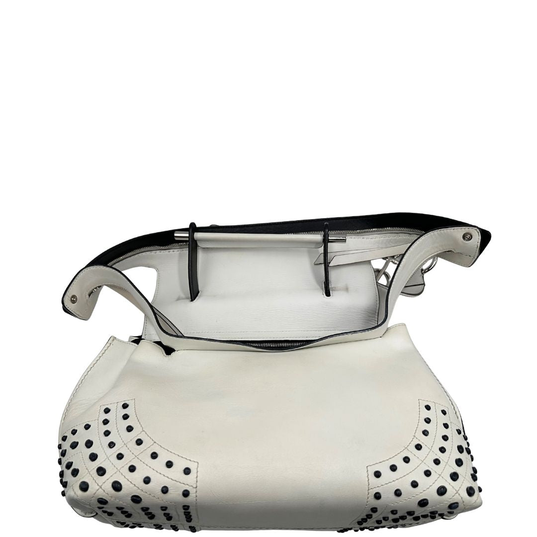 Retro di una borsa Wave Tod's in pelle bianca e nera impreziosita da iconici gommini Tod's sugli angoli della base. Munita di un manico singolo stondato, una tracolla con lettere in catena e pelle, regolabile ed amovibile. Parti metalliche argentate. Dotata di dustbag.