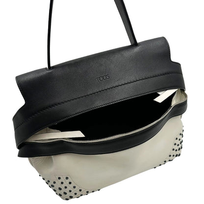 Apertura di una borsa Wave Tod's in pelle bianca e nera impreziosita da iconici gommini Tod's sugli angoli della base. Munita di un manico singolo stondato, una tracolla con lettere in catena e pelle, regolabile ed amovibile. Parti metalliche argentate. Dotata di dustbag.