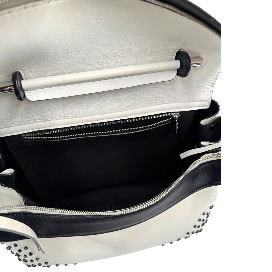 Interno di una borsa Wave Tod's in pelle bianca e nera impreziosita da iconici gommini Tod's sugli angoli della base. Munita di un manico singolo stondato, una tracolla con lettere in catena e pelle, regolabile ed amovibile. Parti metalliche argentate. Dotata di dustbag.