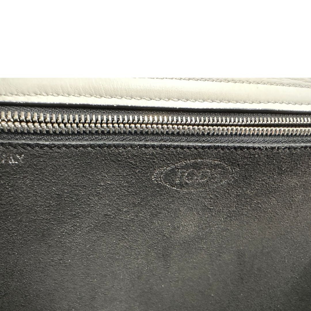 Interno di una borsa Wave Tod's in pelle bianca e nera impreziosita da iconici gommini Tod's sugli angoli della base. Munita di un manico singolo stondato, una tracolla con lettere in catena e pelle, regolabile ed amovibile. Parti metalliche argentate. Dotata di dustbag.