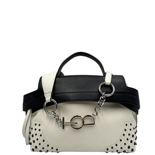 Front di una borsa Wave Tod's in pelle bianca e nera impreziosita da iconici gommini Tod's sugli angoli della base. Munita di un manico singolo stondato, una tracolla con lettere in catena e pelle, regolabile ed amovibile. Parti metalliche argentate. Dotata di dustbag.