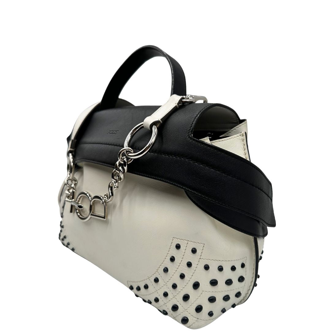 Laterale destro di una borsa Wave Tod's in pelle bianca e nera impreziosita da iconici gommini Tod's sugli angoli della base. Munita di un manico singolo stondato, una tracolla con lettere in catena e pelle, regolabile ed amovibile. Parti metalliche argentate. Dotata di dustbag.