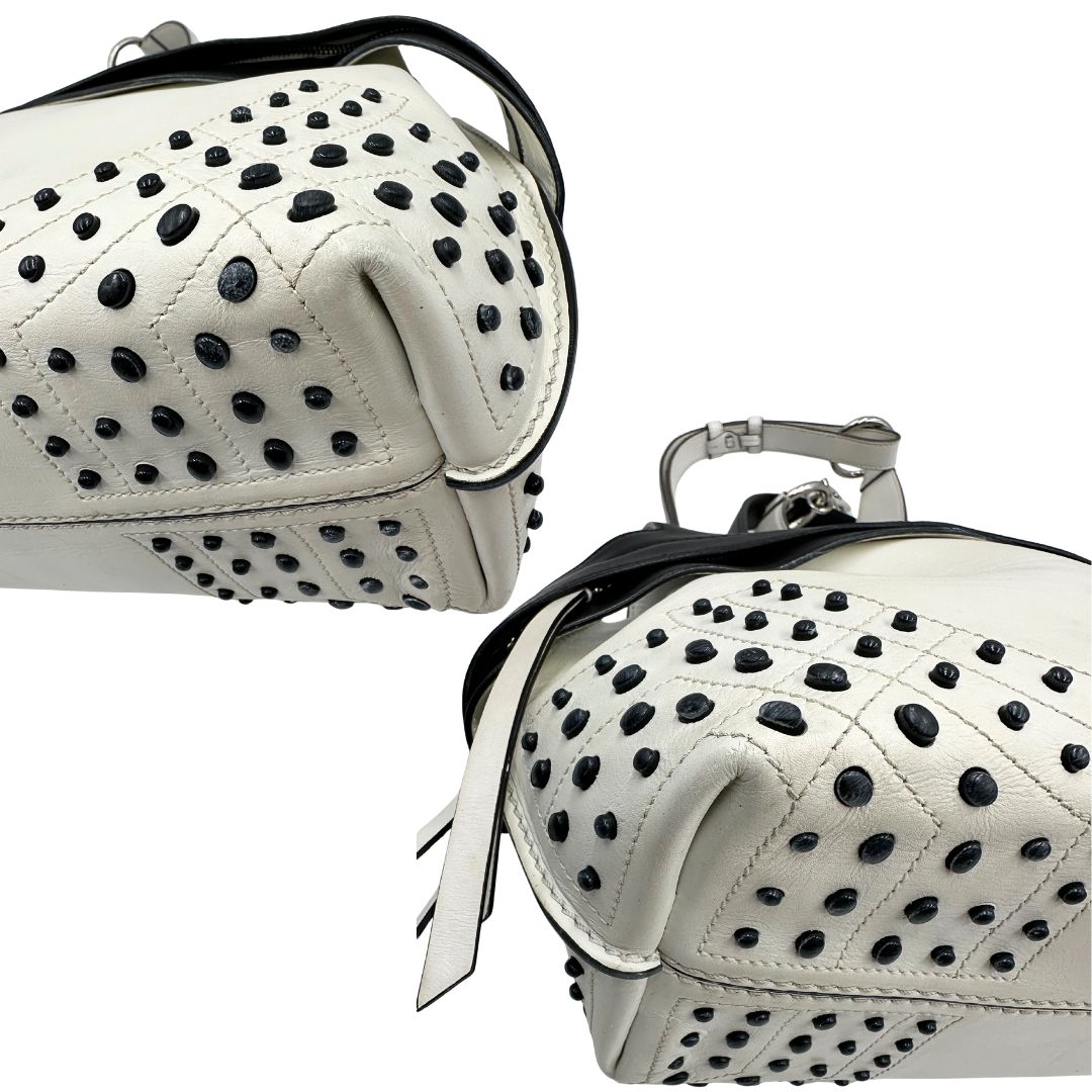 Angoli di una borsa Wave Tod's in pelle bianca e nera impreziosita da iconici gommini Tod's sugli angoli della base. Munita di un manico singolo stondato, una tracolla con lettere in catena e pelle, regolabile ed amovibile. Parti metalliche argentate. Dotata di dustbag.