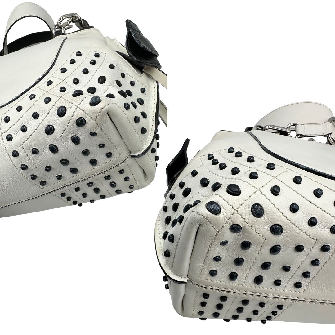 Angoli di una borsa Wave Tod's in pelle bianca e nera impreziosita da iconici gommini Tod's sugli angoli della base. Munita di un manico singolo stondato, una tracolla con lettere in catena e pelle, regolabile ed amovibile. Parti metalliche argentate. Dotata di dustbag.
