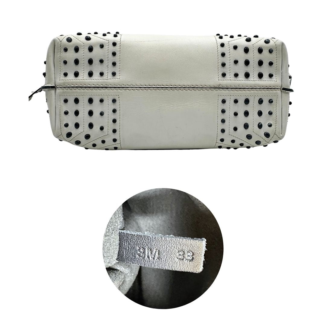 Base e codice di una borsa Wave Tod's in pelle bianca e nera impreziosita da iconici gommini Tod's sugli angoli della base. Munita di un manico singolo stondato, una tracolla con lettere in catena e pelle, regolabile ed amovibile. Parti metalliche argentate. Dotata di dustbag.