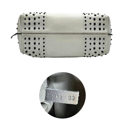 Base e codice di una borsa Wave Tod's in pelle bianca e nera impreziosita da iconici gommini Tod's sugli angoli della base. Munita di un manico singolo stondato, una tracolla con lettere in catena e pelle, regolabile ed amovibile. Parti metalliche argentate. Dotata di dustbag.