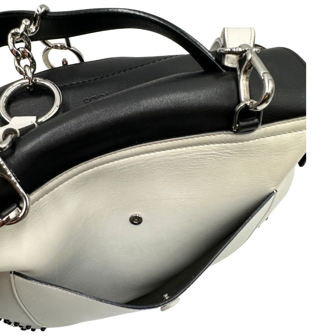 Interno di una borsa Wave Tod's in pelle bianca e nera impreziosita da iconici gommini Tod's sugli angoli della base. Munita di un manico singolo stondato, una tracolla con lettere in catena e pelle, regolabile ed amovibile. Parti metalliche argentate. Dotata di dustbag.