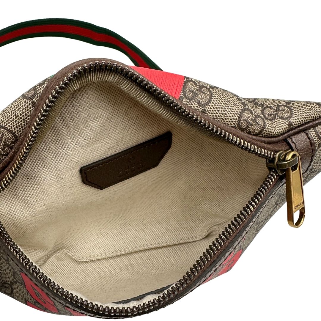 Interno di un marsupio Gucci in canvas beige GG con metalleria dorata e finiture in pelle marroni. Stampa Gucci Tiger e fascia Web su front e retro. Tracolla in tessuto Web verde/rosso, regolabile. Completo di dustbag. Indossabile a marsupio o crossbody.
