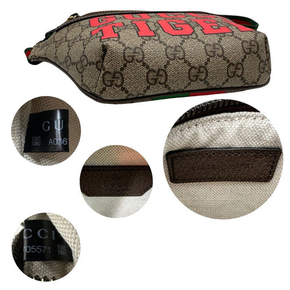 Base e codici di un marsupio Gucci in canvas beige GG con metalleria dorata e finiture in pelle marroni. Stampa Gucci Tiger e fascia Web su front e retro. Tracolla in tessuto Web verde/rosso, regolabile. Completo di dustbag. Indossabile a marsupio o crossbody.