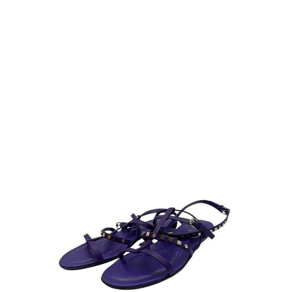 Sandali Tod’s in pelle viola con fasce incrociate e borchie metalliche argentate. Presentano una chiusura con cinturino e la suola con i classici gommini in gomma. Completi di scatola e dustbag.