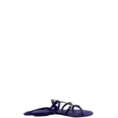 Sandali Tod’s in pelle viola con fasce incrociate e borchie metalliche argentate. Presentano una chiusura con cinturino e la suola con i classici gommini in gomma. Completi di scatola e dustbag.