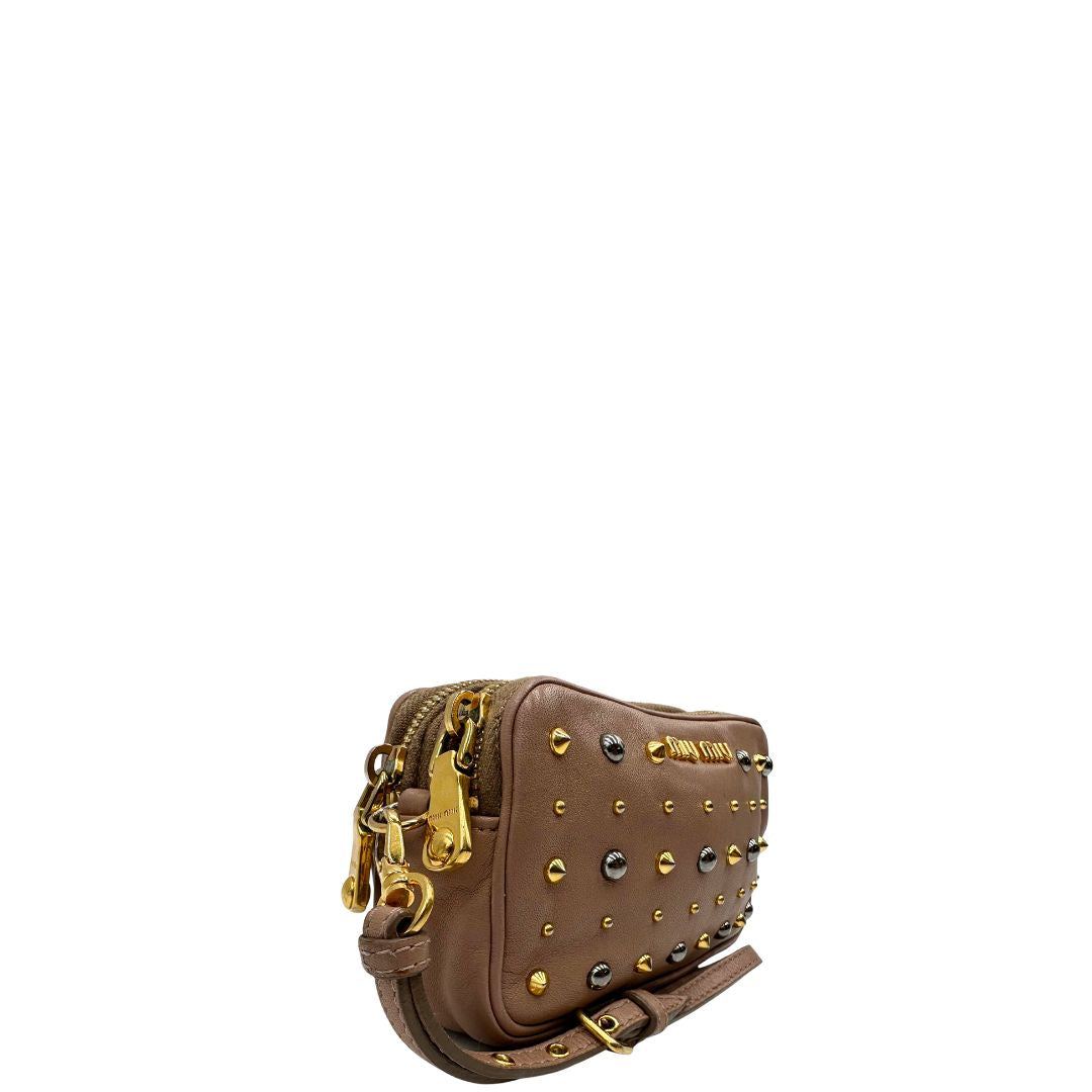 lato Pochette Miu Miu in pelle color taupe con doppia zip, borchie metalliche frontali oro e argento con dettagli hardware dorati. Dotata di polsino regolabile e due scomparti interni foderati in pelle. Completa di scatola.