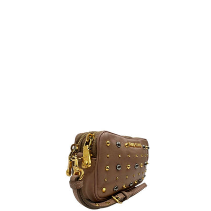 lato Pochette Miu Miu in pelle color taupe con doppia zip, borchie metalliche frontali oro e argento con dettagli hardware dorati. Dotata di polsino regolabile e due scomparti interni foderati in pelle. Completa di scatola.