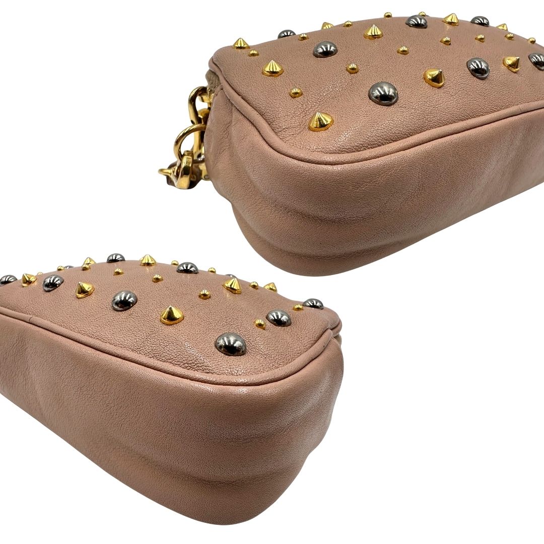 angoli Pochette Miu Miu in pelle color taupe con doppia zip, borchie metalliche frontali oro e argento con dettagli hardware dorati. Dotata di polsino regolabile e due scomparti interni foderati in pelle. Completa di scatola. 