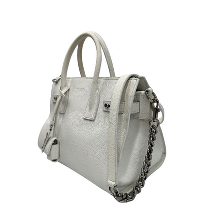 Laterale destro di una Sac De Jour small Saint Laurent in pelle martellata bianco gesso con doppi manici stondati e tracolla in catena e pelle, regolabile ed amovibile. Parti metalliche argentate. Munita di clochette con lucchetto e chiavi.