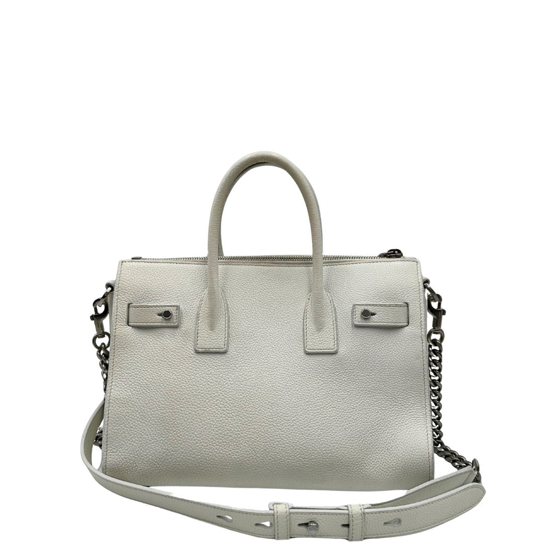 Retro di una Sac De Jour small Saint Laurent in pelle martellata bianco gesso con doppi manici stondati e tracolla in catena e pelle, regolabile ed amovibile. Parti metalliche argentate. Munita di clochette con lucchetto e chiavi.