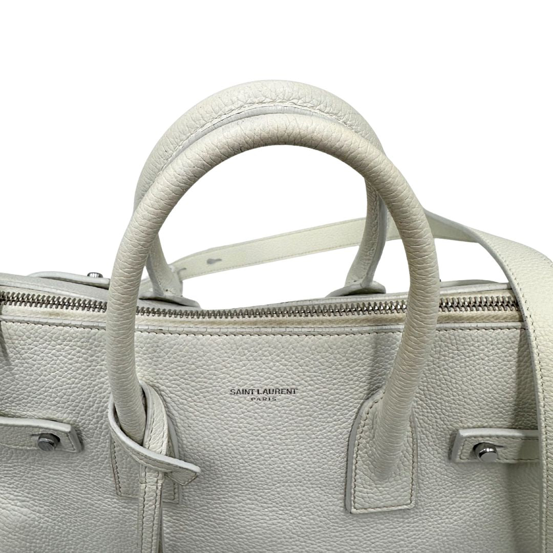Manici di una Sac De Jour small Saint Laurent in pelle martellata bianco gesso con doppi manici stondati e tracolla in catena e pelle, regolabile ed amovibile. Parti metalliche argentate. Munita di clochette con lucchetto e chiavi.