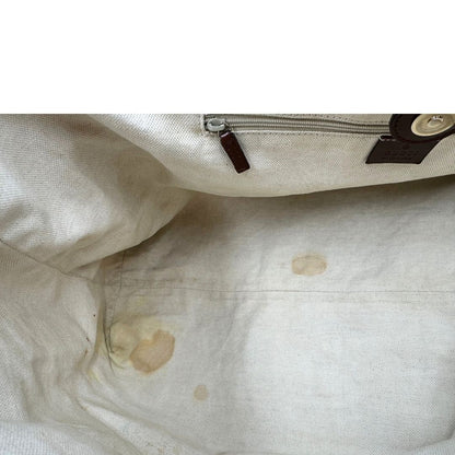 Interno di una borsa Gucci Sukey in tessuto beige GG con finiture in pelle marrone mogano, doppi manici stondati e ciondolo con doppie G incrociate. Rifinita con parti metalliche dorate. Indossabile a spalla.