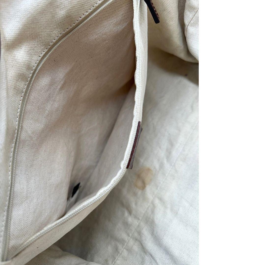 Interno di una borsa Gucci Sukey in tessuto beige GG con finiture in pelle marrone mogano, doppi manici stondati e ciondolo con doppie G incrociate. Rifinita con parti metalliche dorate. Indossabile a spalla.