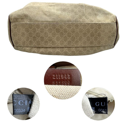 Base e codici di una borsa Gucci Sukey in tessuto beige GG con finiture in pelle marrone mogano, doppi manici stondati e ciondolo con doppie G incrociate. Rifinita con parti metalliche dorate. Indossabile a spalla.