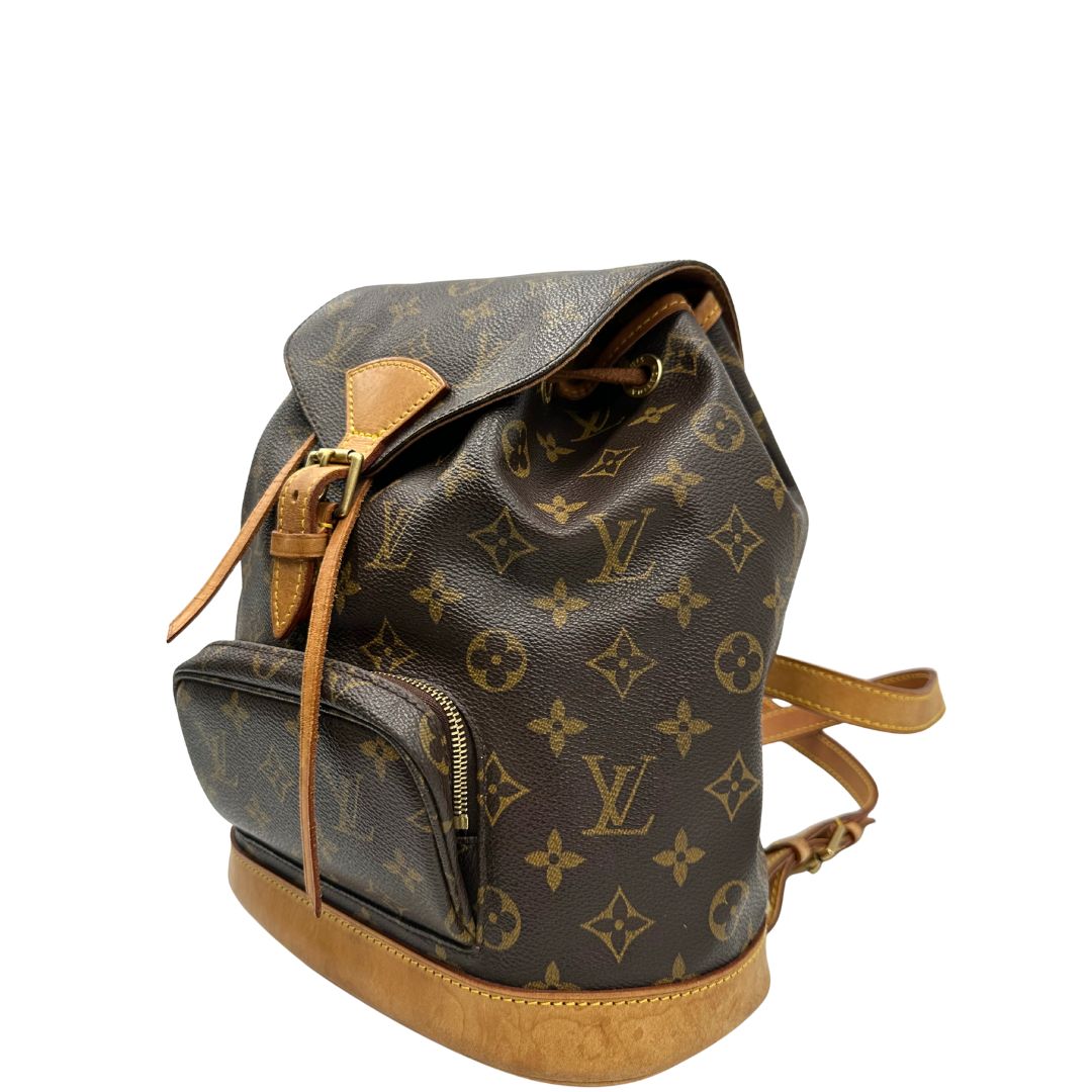 lato Zaino Montsouris mini in canvas marrone monogram con finiture in vacchetta naturale e parti metalliche dorate, munito di un anello sulla parte superiore e due bretelle in vacchetta regolabili con fibbie. Completo di dustbag, di lusso, originale, ottime condizioni. 