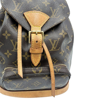 Zaino Montsouris mini in canvas marrone monogram con finiture in vacchetta naturale e parti metalliche dorate, munito di un anello sulla parte superiore e due bretelle in vacchetta regolabili con fibbie. Completo di dustbag, di lusso, originale, ottime condizioni. 