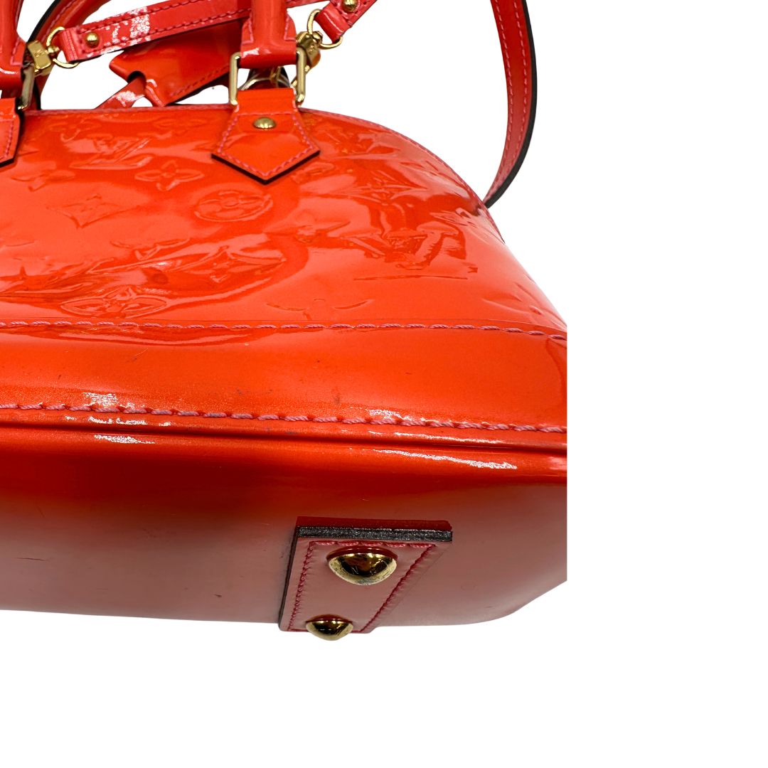 base Borsa Louis Vuitton Alma BB in pelle Vernis arancione corallo monogram e parti metalliche dorate. Munita di doppi manici stondati e una tracolla amovibile, dotata di clochette porta chiavi. Completa di dustbag, lucchetto e chiavi, di lusso, originale, ottime condizioni, usata. 