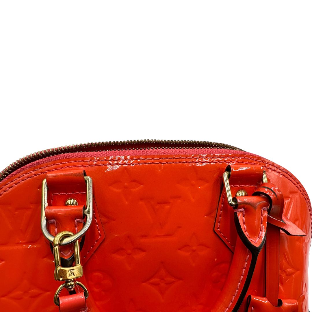 metalleria Borsa Louis Vuitton Alma BB in pelle Vernis arancione corallo monogram e parti metalliche dorate. Munita di doppi manici stondati e una tracolla amovibile, dotata di clochette porta chiavi. Completa di dustbag, lucchetto e chiavi, di lusso, originale, ottime condizioni, usata. 