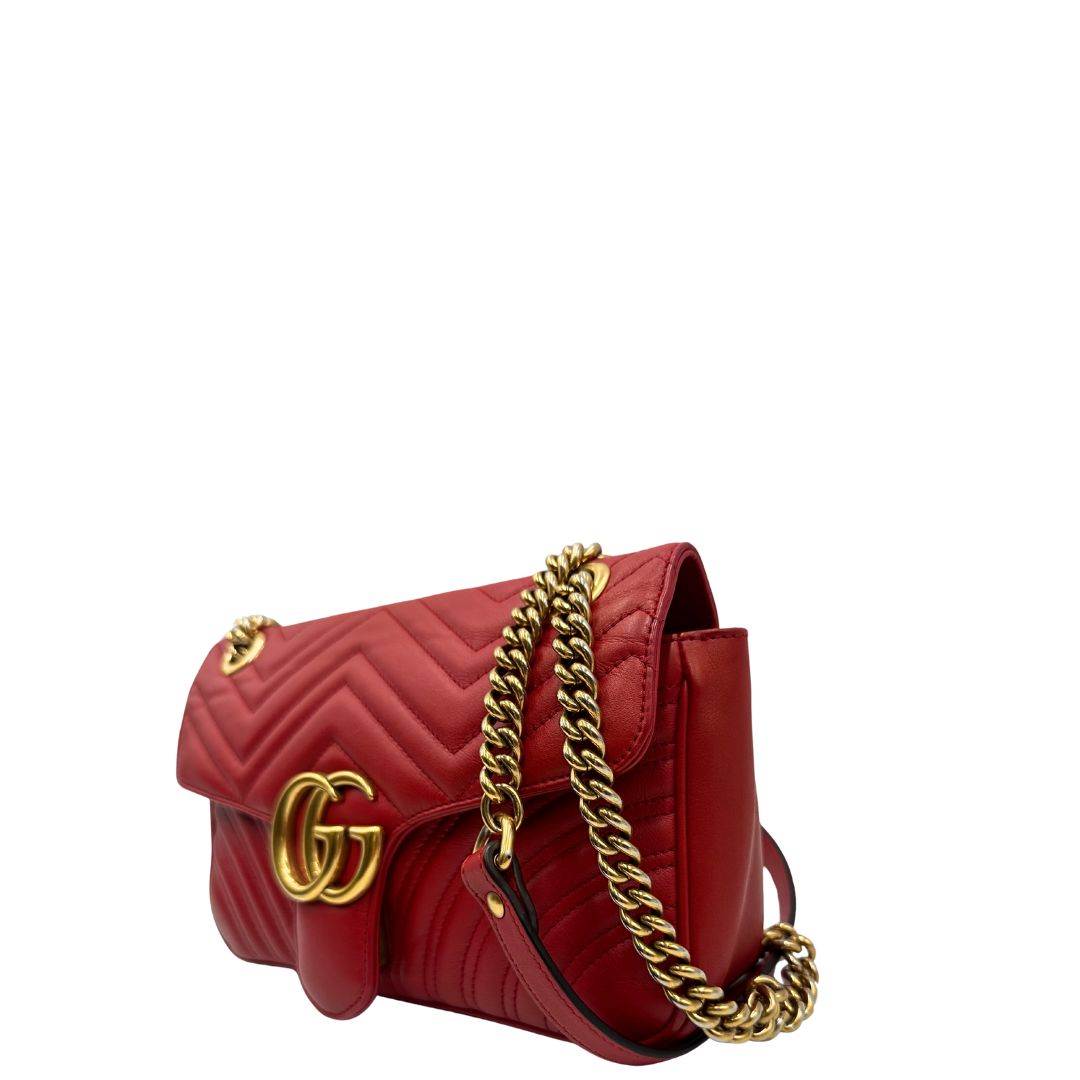 Lato sinistro di una Borsa Gucci Marmont in pelle matelassé rossa con tracolla scorrevole in catena e spallaccio in pelle, rifinita con parti metalliche dorate. Completa di dustbag. Originale, usato, di lusso, in ottime condizioni.
