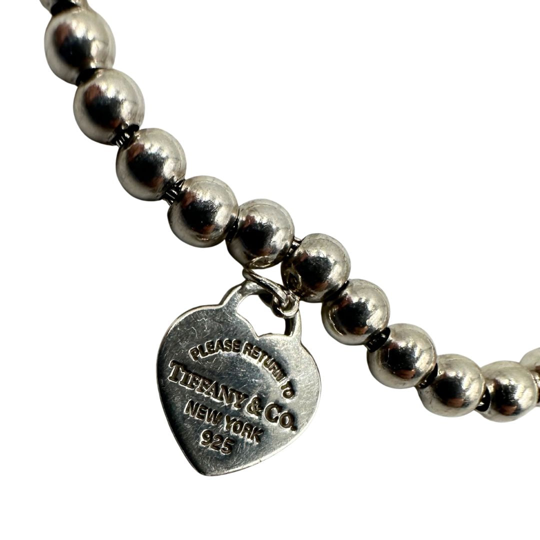 Bracciale Tiffany&Co. della collezione Return to Tiffany in argento 925 composto da sfere circolari e ciondolo cuore smaltato in verde Tiffany. Completo di scatola e sacchetto anti polvere.