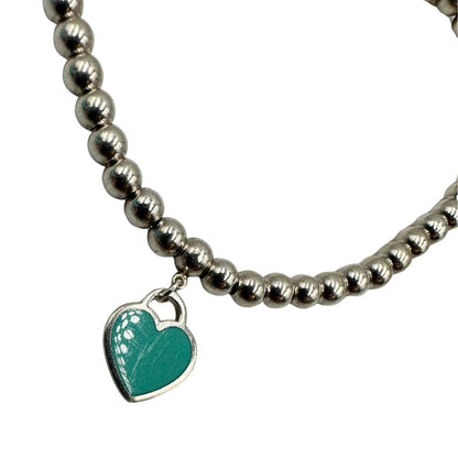 Bracciale Tiffany&Co. della collezione Return to Tiffany in argento 925 composto da sfere circolari e ciondolo cuore smaltato in verde Tiffany. Completo di scatola e sacchetto anti polvere.
