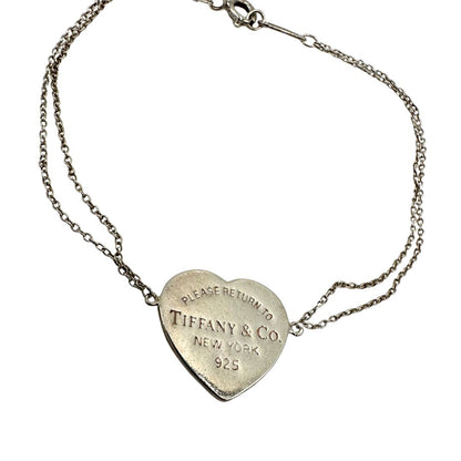 Bracciale Tiffany&Co. in argento 925, caratterizzato da una doppia catenina sottile e dal celebre cuore inciso “Please Return to Tiffany&Co. New York 925”. Munito di busta e sacchetto anti polvere.