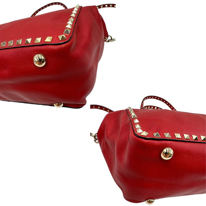 Angoli di una borsa Valentino Garavani in pelle rossa con parti metalliche dorate; impreziosita da borchie piramidali e munita di doppi manici e tracolla amovibile. Completa di dustbag. 