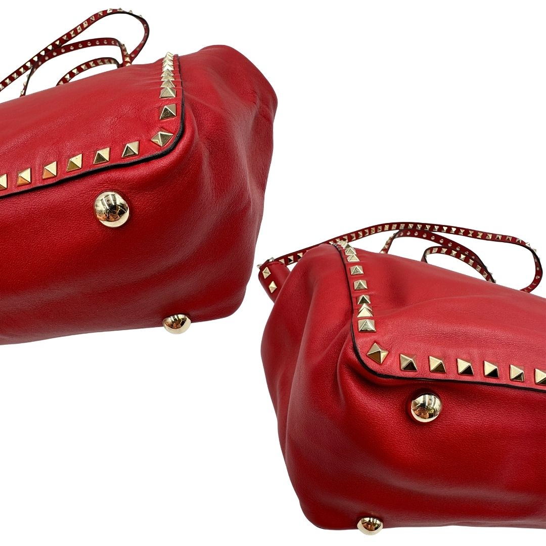 Angoli di una borsa Valentino Garavani in pelle rossa con parti metalliche dorate; impreziosita da borchie piramidali e munita di doppi manici e tracolla amovibile. Completa di dustbag. 