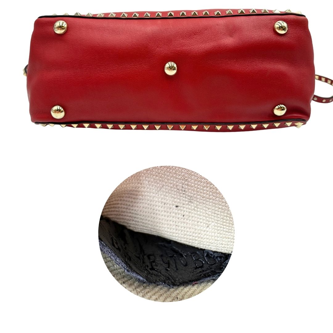 Base e codice di una borsa Valentino Garavani in pelle rossa con parti metalliche dorate; impreziosita da borchie piramidali e munita di doppi manici e tracolla amovibile. Completa di dustbag. 