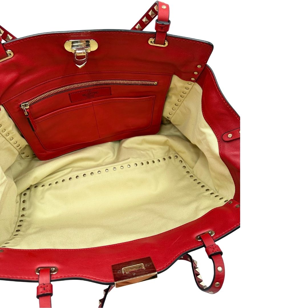 Interno di una borsa Valentino Garavani in pelle rossa con parti metalliche dorate; impreziosita da borchie piramidali e munita di doppi manici e tracolla amovibile. Completa di dustbag. 