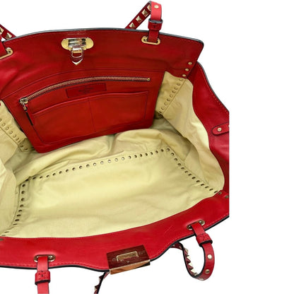 Interno di una borsa Valentino Garavani in pelle rossa con parti metalliche dorate; impreziosita da borchie piramidali e munita di doppi manici e tracolla amovibile. Completa di dustbag. 