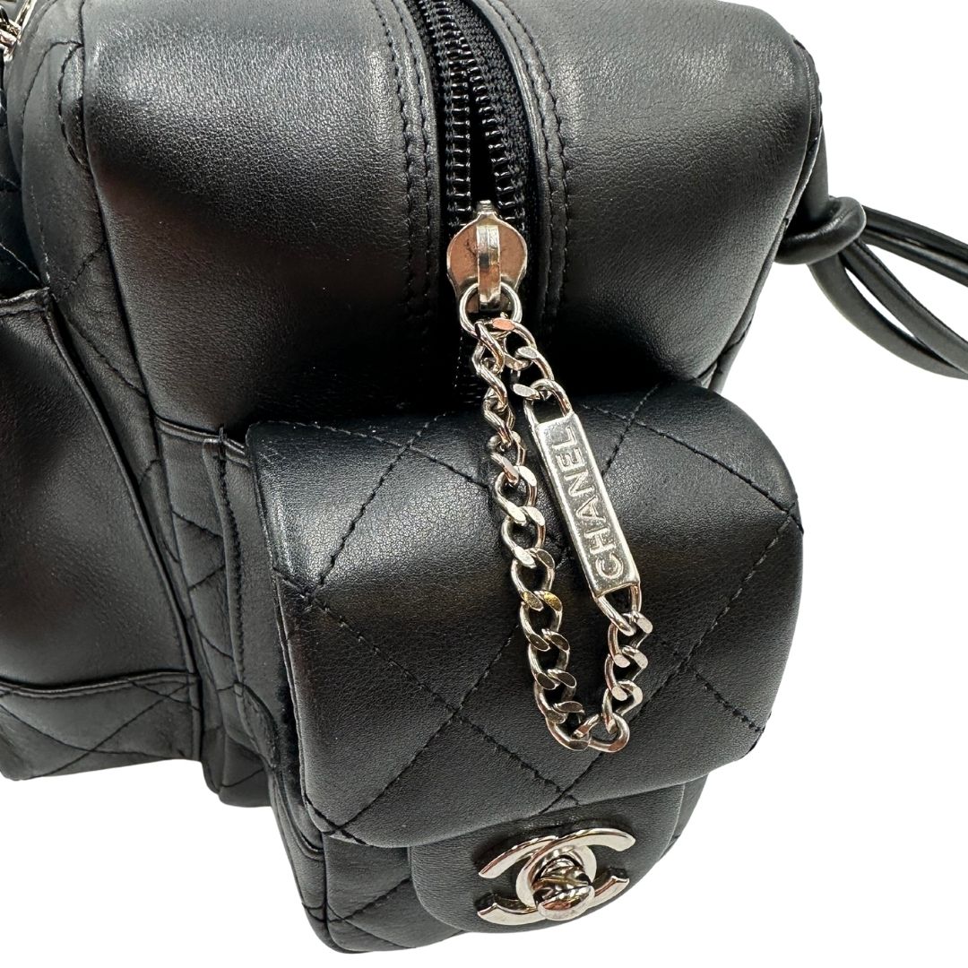 Dettagli metallici di una borsa Cambon Reporter Chanel in pelle trapuntata nera e doppie C bianche sul front, con tasche per accessori e doppi manici medio lunghi, rifinita con parti metalliche argentate. Completa di dustbag e card d'autenticità. Indossabile a spalla.