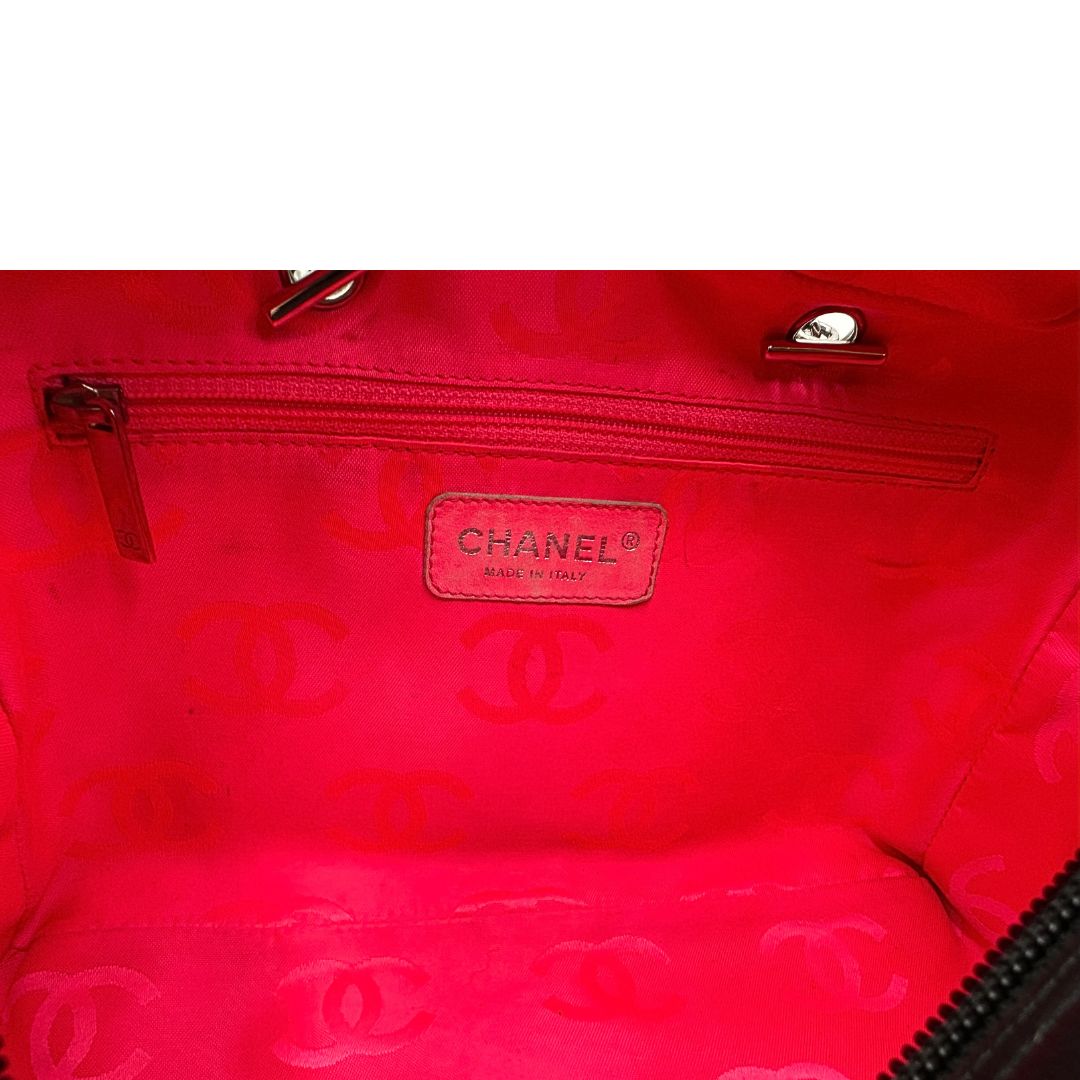 Interno di una borsa Cambon Reporter Chanel in pelle trapuntata nera e doppie C bianche sul front, con tasche per accessori e doppi manici medio lunghi, rifinita con parti metalliche argentate. Completa di dustbag e card d'autenticità. Indossabile a spalla.